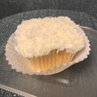 Coconut cupcake with cream cheese frosting and coconut flakes on top. Coconut