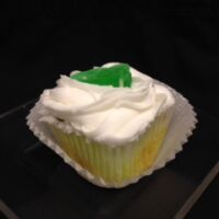 A Key Lime cupcake with Key Lime pudding filling, topped with vanilla buttercream and finished with a lime candy piece. Key Lime
