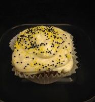 A honey cupcake topped with honey cream cheese and finished with black and yellow non-perils. Honey