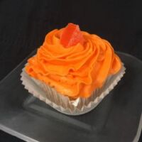 An orange cupcake topped with orange cream cheese icing and finished with an orange candy wedge. Orange Creamsicle