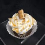 A chocolate cupcake with peanut butter chips, topped with vanilla buttercream and finished with a piece of a Snickers candy bar. Snickers