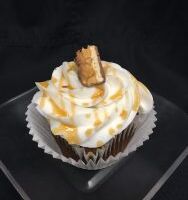 A chocolate cupcake with peanut butter chips, topped with vanilla buttercream and finished with a piece of a Snickers candy bar. Snickers