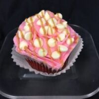 A red velvet cupcake with a white chocolate peanut butter ganache filling, topped with a white chocolate buttercream icing, and finished with white chocolate chips and a peanut butter drizzle. Peanut Butter Blush