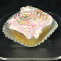 A Vanilla Cupcake with a fudge filling, pink buttercream icing, and non nonpareils on top. Sugar Rush