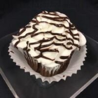 A chocolate cupcake with a white chocolate ganache filling, topped with vanilla buttercream and finished with a chocolate ganache drizzle. Black Tie
