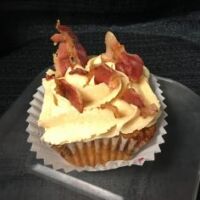 A brown sugar bacon cupcake topped with brown sugar cream cheese and bacon pieces. Brown Sugar Bacon