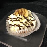 A banana cupcake with banana buttercream, filled and drizzled with chocolate and topped with a banana chip. Chocolate Monkey