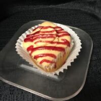 A vanilla cupcake with grape jelly filling, topped with peanut butter buttercream and a grape jelly drizzle. PB&J