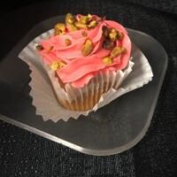 A cherry, pistachio cupcake filled with pistachio pudding, covered in cherry cream cheese frosting then topped with crushed pistachios. Cherry Pistachio