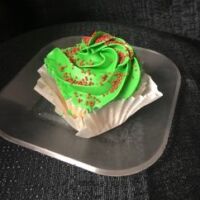 A vanilla cupcake with an orange white chocolate ganache filling, topped with green colored, orange flavored cream cheese frosting, finished with red non pareils. Holly Jolly