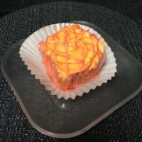 A strawberry cupcake with an orange white chocolate ganache filling, orange cream cheese icing, and a strawberry glaze drizzled on top. Strawberry Orange