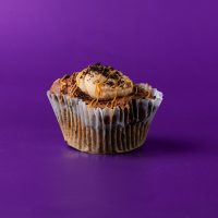 A cupcake made with peanut butter Oreos, filled with peanut butter and crushed Oreo cookies, iced in peanut butter and chocolate buttercream, and drizzled with peanut butter before being topped with even more Oreo pieces. Peanut Butter Oreo cupcake