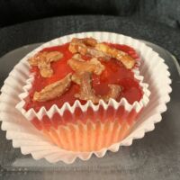 Strawberry cupcake with a cream cheese filling topped with strawberry glaze and candied pretzel bits. Strawberry Pretzel