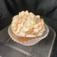 Vanilla cupcake filled with white peanut butter ganache, iced with vanilla buttercream and topped with white morsels and peanut butter drizzle. White Chocolate Peanut Butter