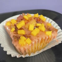 A Filipino inspired cheese cupcake baked with bacon with a strawberry preserve filling, strawberry glaze, and topped with bacon bits and cheese cubes. Strawberry Cheddar Bacon